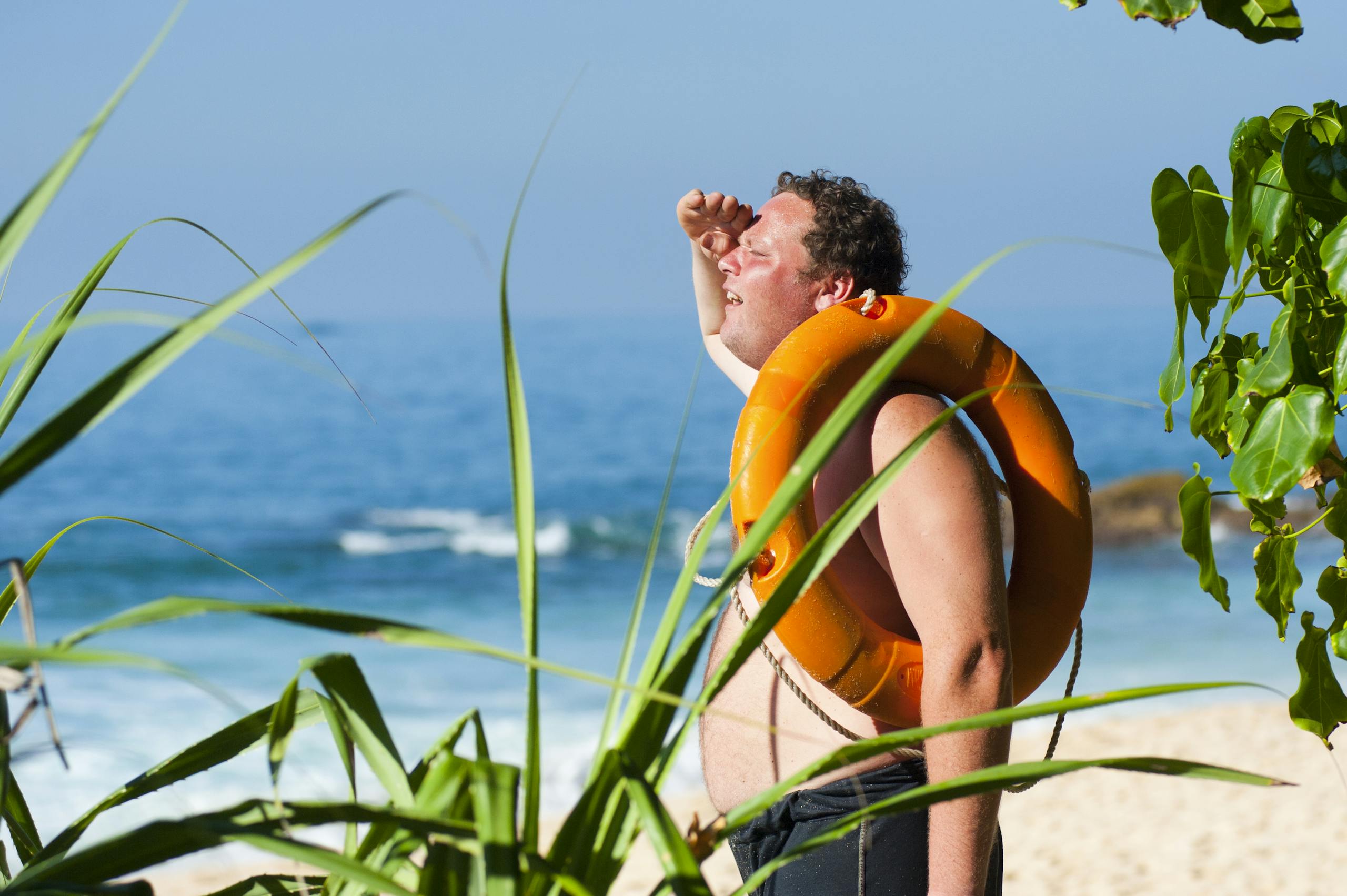 A man with a lifebuoy enjoys a sunny day at the beautiful tropical beach of Unawatuna, Sri Lanka.